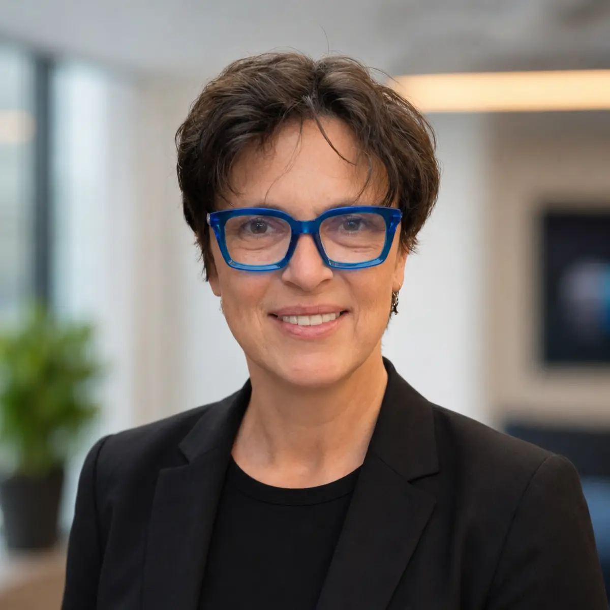 Angelina Filip wearing bright blue glasses and a black blazer
